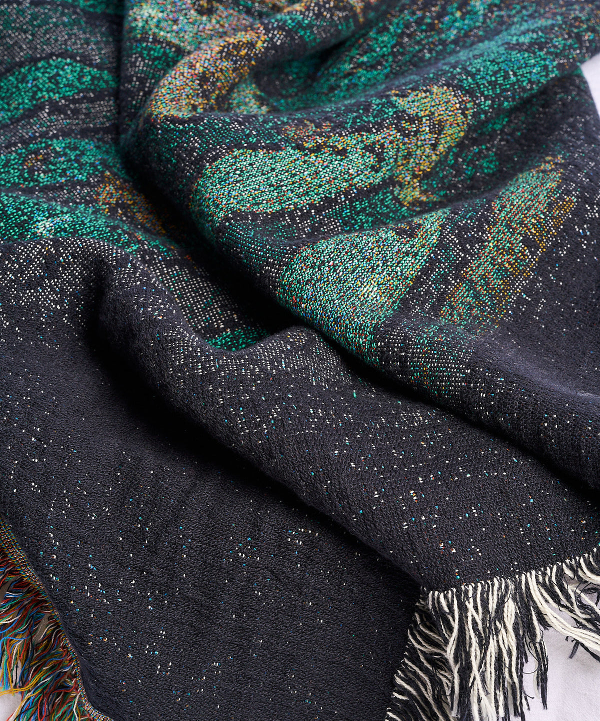 Close-up of the Ghost Pals woven blanket showing the dark teal weave and fringe