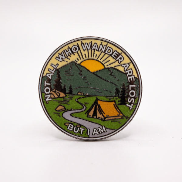 Camping Mountains enamel pin, a tent by a winding river under green mountains and a yellow sunrise, reading Not All Who Wander Are Lost, But I Am