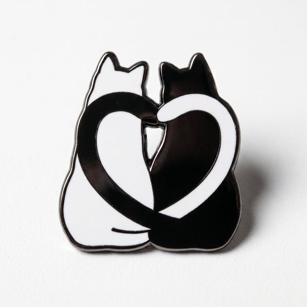 Cat Love Heart enamel pin, a white cat and a black cat sitting side by side with their tails curled into a heart