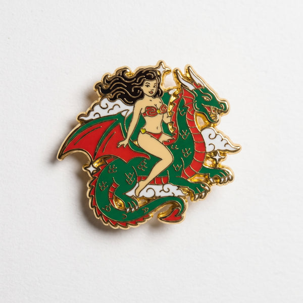 Dragon Maiden enamel pin, a dark-haired pin-up girl in a red bikini riding a coiled green and red dragon