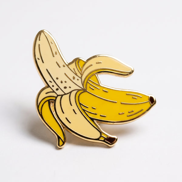 Peeling Banana enamel pin, a half-peeled yellow banana with the pale fruit showing, outlined in gold