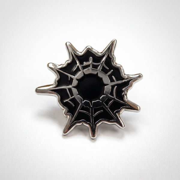 Spider Web enamel pin, a jagged black spider web with shiny raised silver strands