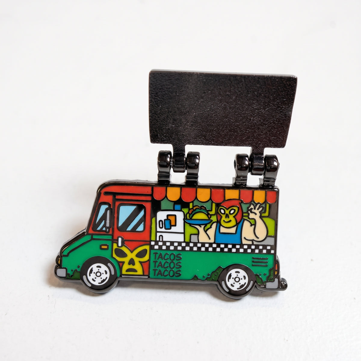Holy Guacamole Taco Truck pin with its hinged side flipped open, revealing a luchador taco chef serving through the window
