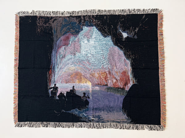 Sea Grotto woven blanket showing figures by the water inside a dark sea cave glowing with pink and violet sunset light, after Joseph Wright of Derby
