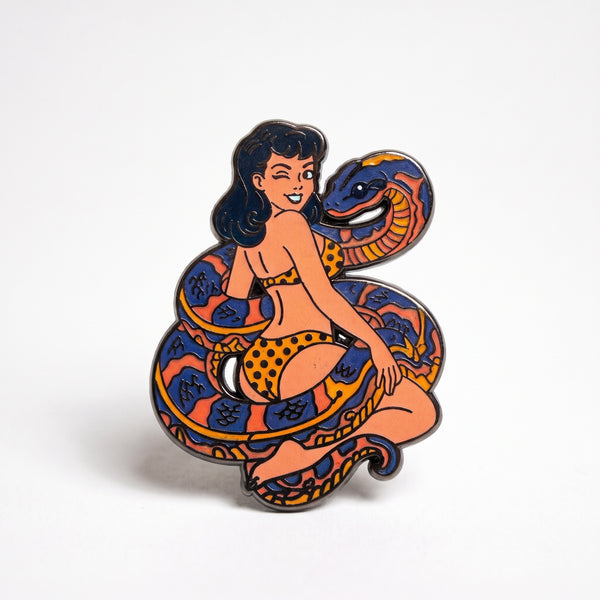 Snake Charmer enamel pin, a pin-up girl wrapped in a large orange and black snake