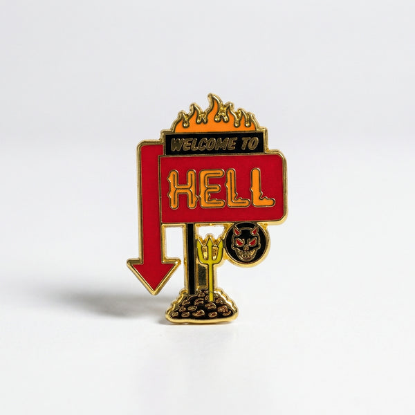 Enamel pin shaped like a roadside sign reading Welcome to Hell with flames and a red arrow