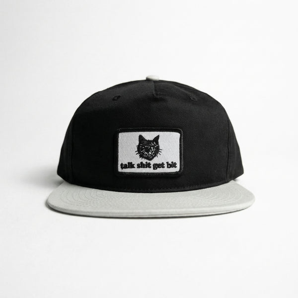 Black and grey snapback hat with a white patch featuring a black cat and the text talk shit get bit