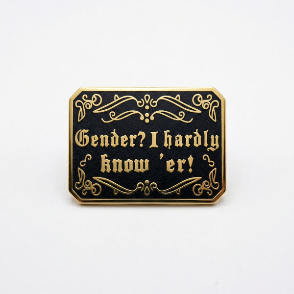 Black and gold enamel pin with gothic text reading Gender? I hardly know 'er!
