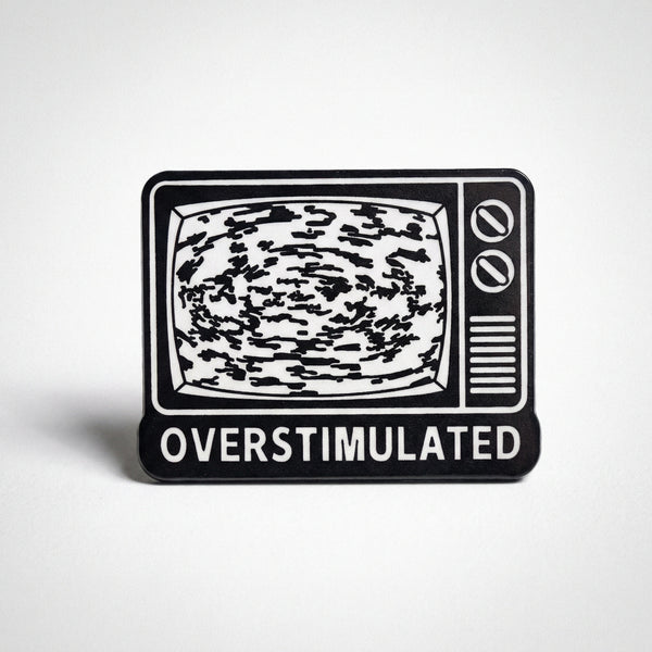 Black and white enamel pin of retro TV with static screen and Overstimulated text