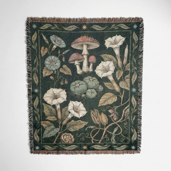Woven cotton blanket with botanical illustrations of mushrooms and flowers on a dark background.