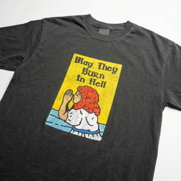 Charcoal washed t-shirt with a yellow graphic of a praying woman and the text May They Burn In Hell.