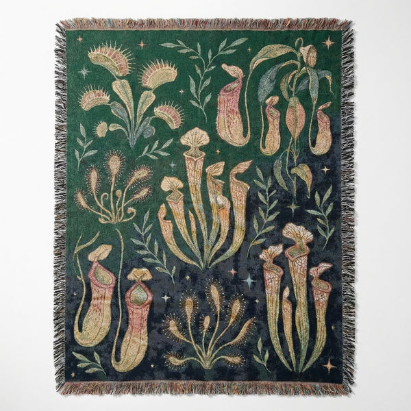 Woven blanket with carnivorous plant illustrations including Venus flytraps and pitcher plants on a dark green background.
