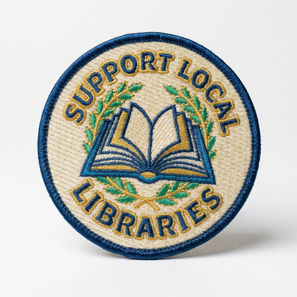 Circular embroidered patch with blue and gold thread showing an open book and the text Support Local Libraries