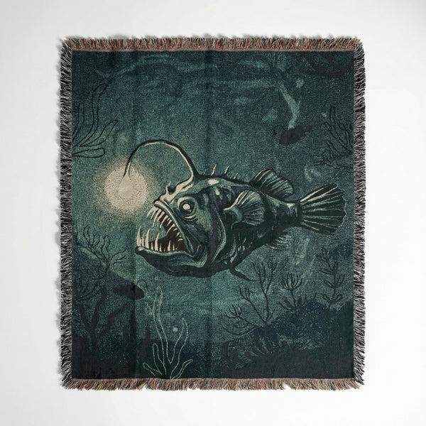 Woven cotton throw blanket featuring a deep sea anglerfish design in dark green and teal.
