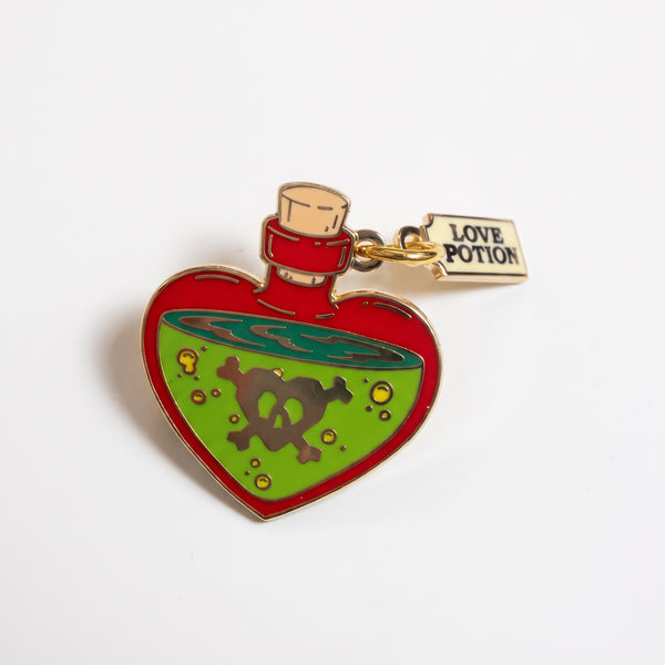 Love Potion enamel pin, a red heart-shaped bottle of green potion with a skull and a Love Potion tag
