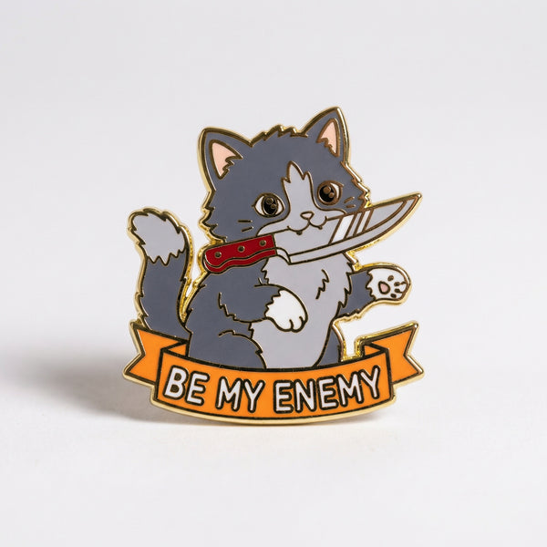 Grey and white cat enamel pin holding a knife with Be My Enemy banner