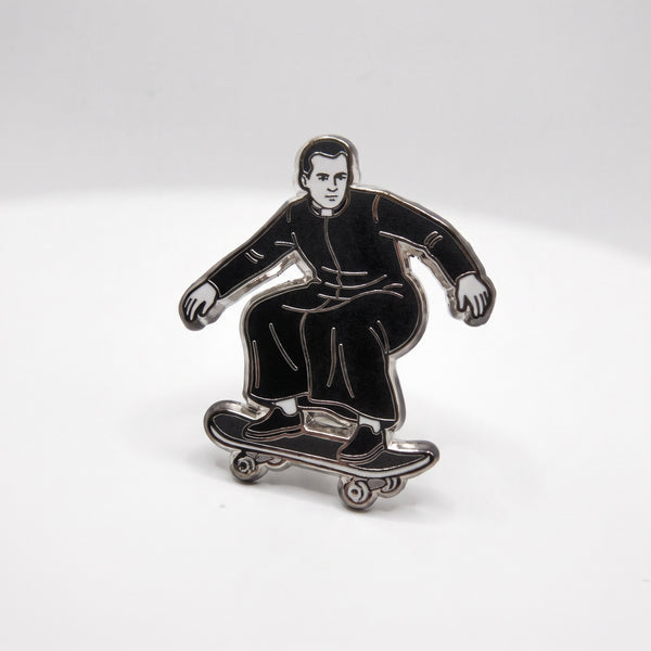 Skating Priest enamel pin, a priest in black robes riding a skateboard