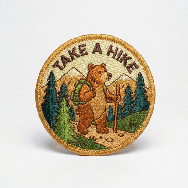 Embroidered iron-on patch of a brown bear hiking in the mountains