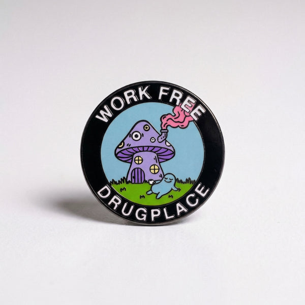 Circular black enamel pin with a purple mushroom house and text reading Work Free Drugplace.