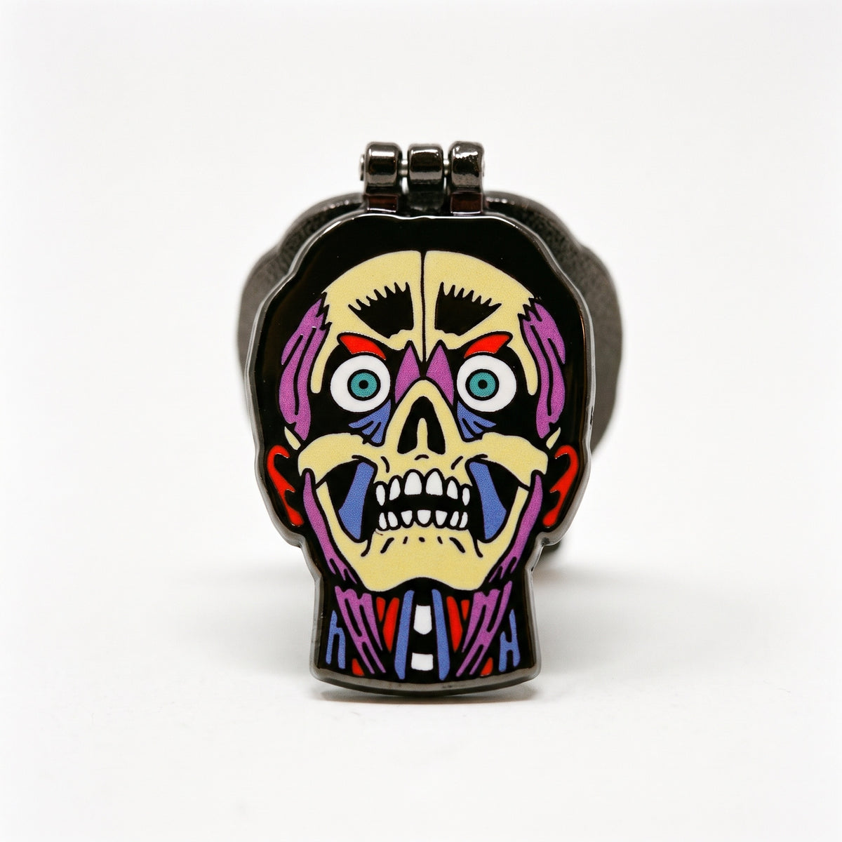 Other side of the Skin Deep Deluxe pin, a grinning cream skull face with purple and blue muscle and staring teal eyes