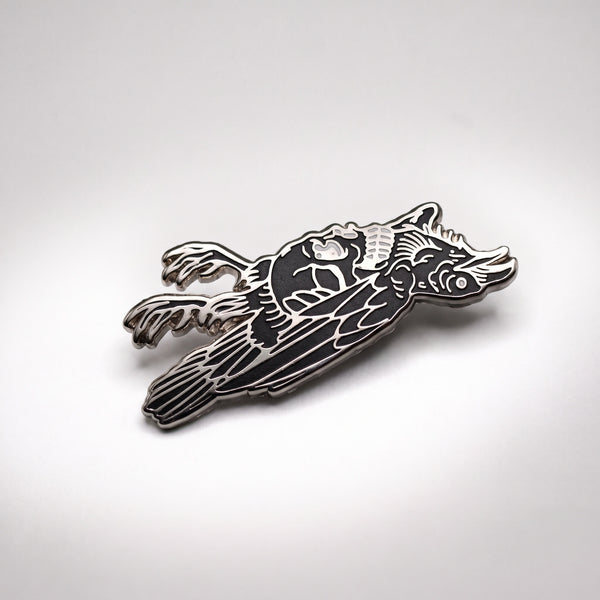 Dead Crow enamel pin, a black crow lying on its back with curled feet and exposed white ribs, outlined in silver