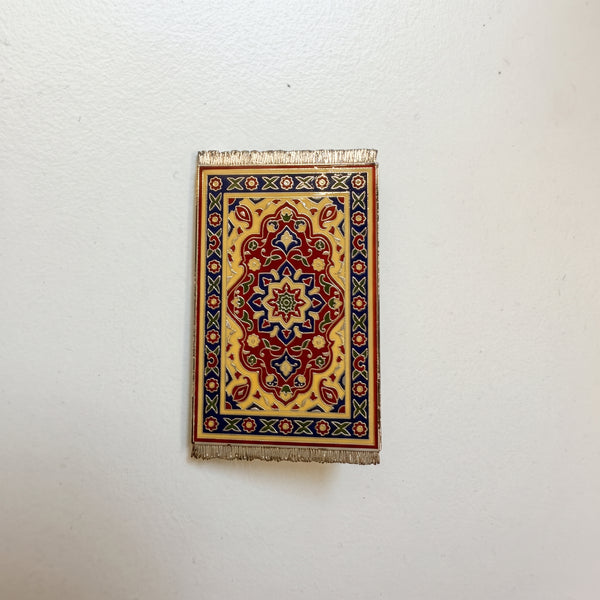Persian Rug enamel pin, a tiny ornate rug in red, cream and navy with silver fringe at each end